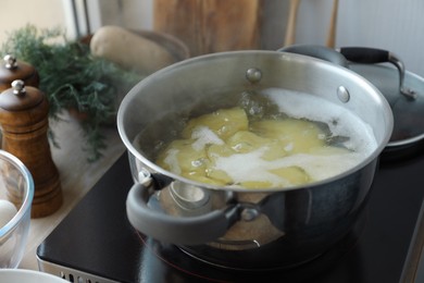 Photo of Boiling potatoes in pot on stove in kitchen