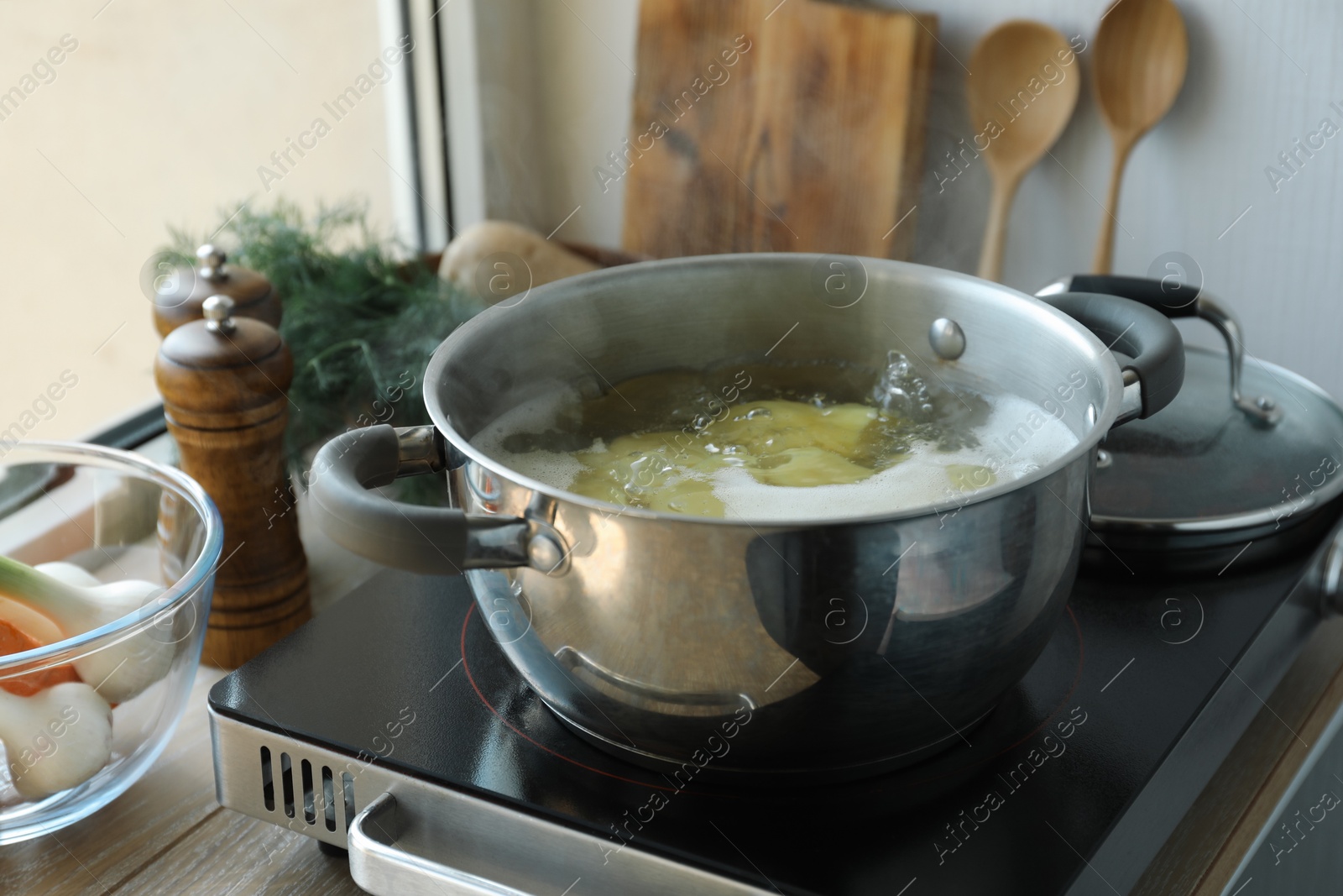 Photo of Boiling potatoes in pot on stove in kitchen