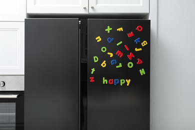 Photo of Word Happy made of bright magnetic letters on fridge indoors. Learning alphabet