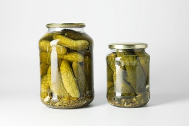 Pickled cucumbers in jars on light background