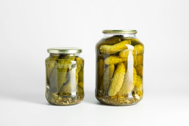 Pickled cucumbers in jars on light background