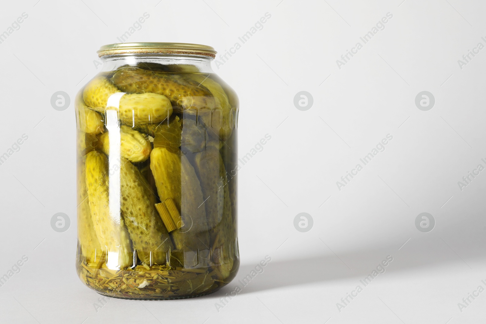 Photo of Pickled cucumbers in jar on light background. Space for text