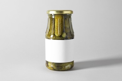 Pickled cucumbers in jar on light background