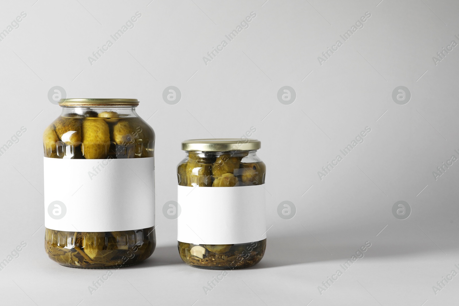 Photo of Pickled cucumbers in jars on light background. Space for text