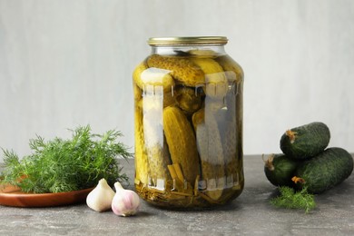 Photo of Pickles in jar, fresh cucumbers, dill and garlic on grey table