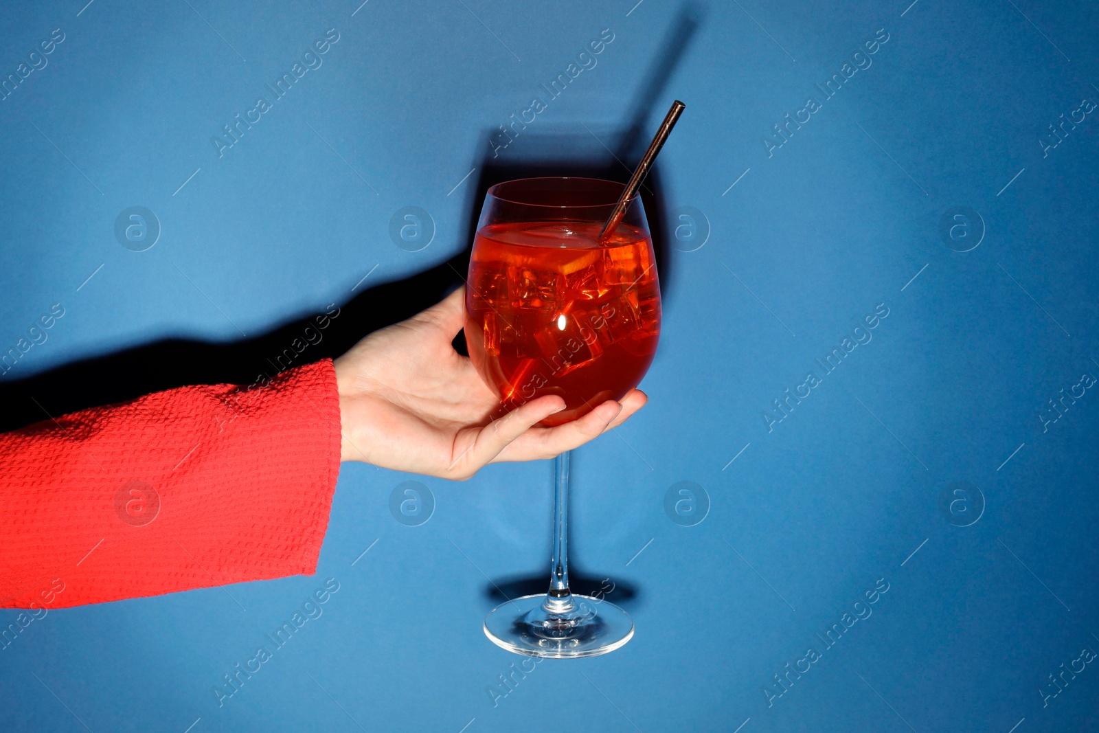 Photo of Woman with glass of refreshing cocktail on blue background, closeup