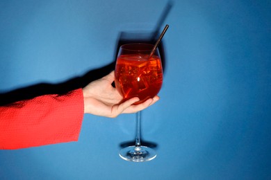 Photo of Woman with glass of refreshing cocktail on blue background, closeup