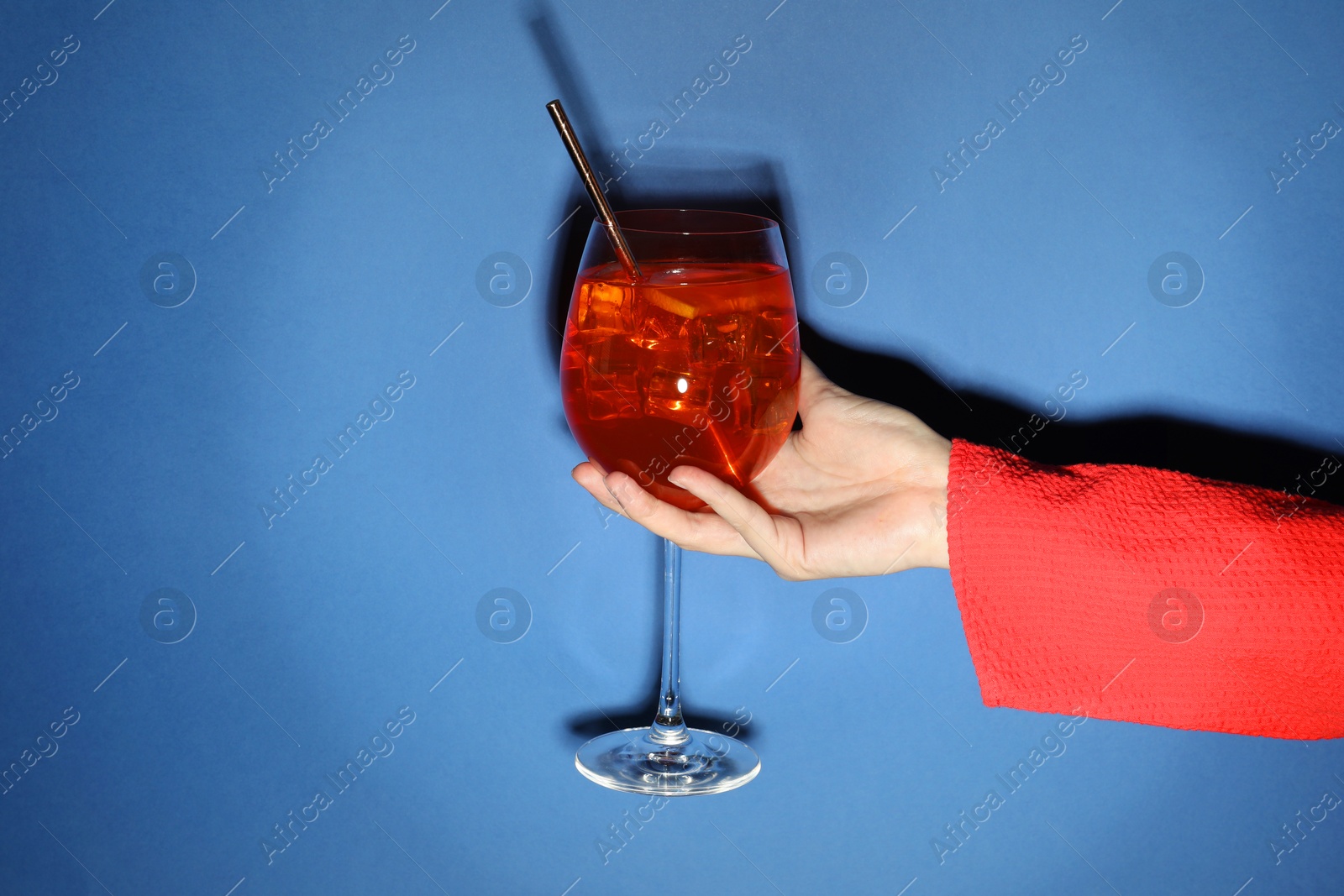 Photo of Woman with glass of refreshing cocktail on blue background, closeup