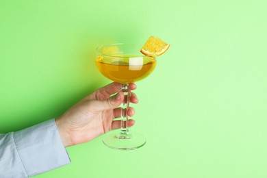 Photo of Woman with glass of refreshing cocktail on green background, closeup. Space for text