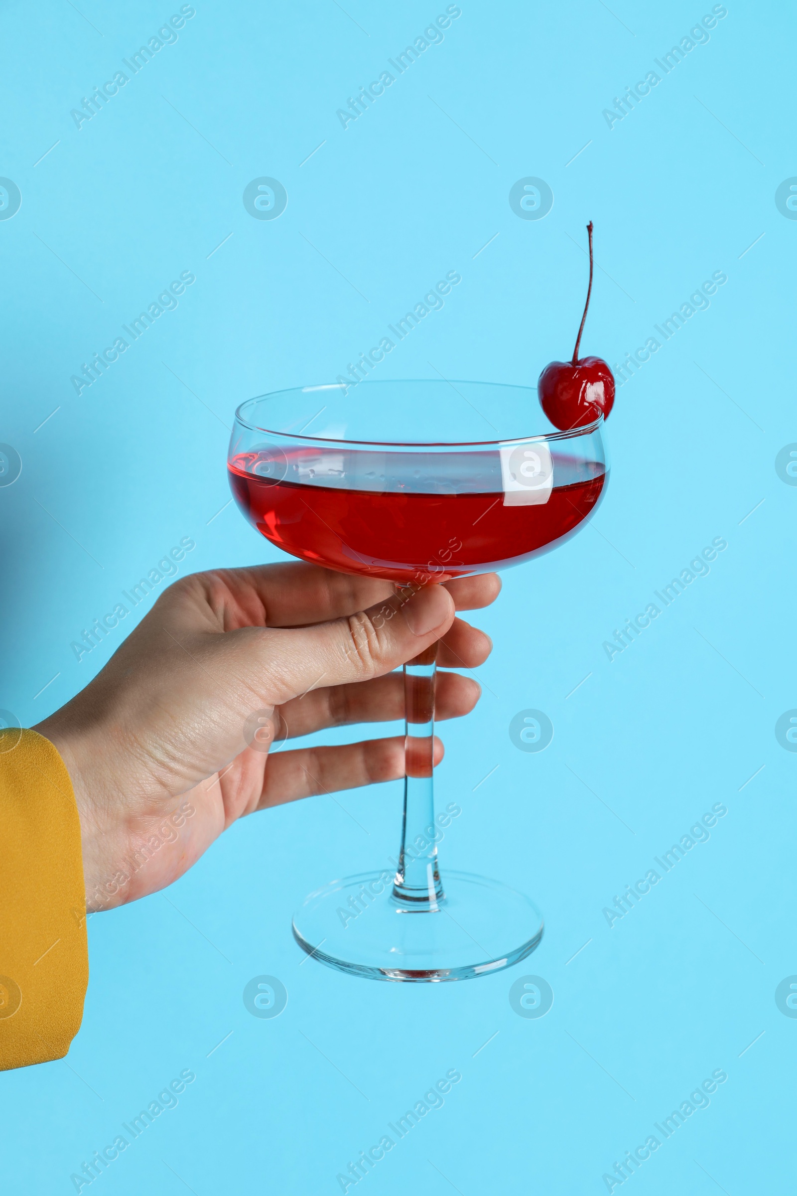 Photo of Woman with glass of refreshing cocktail on light blue background, closeup