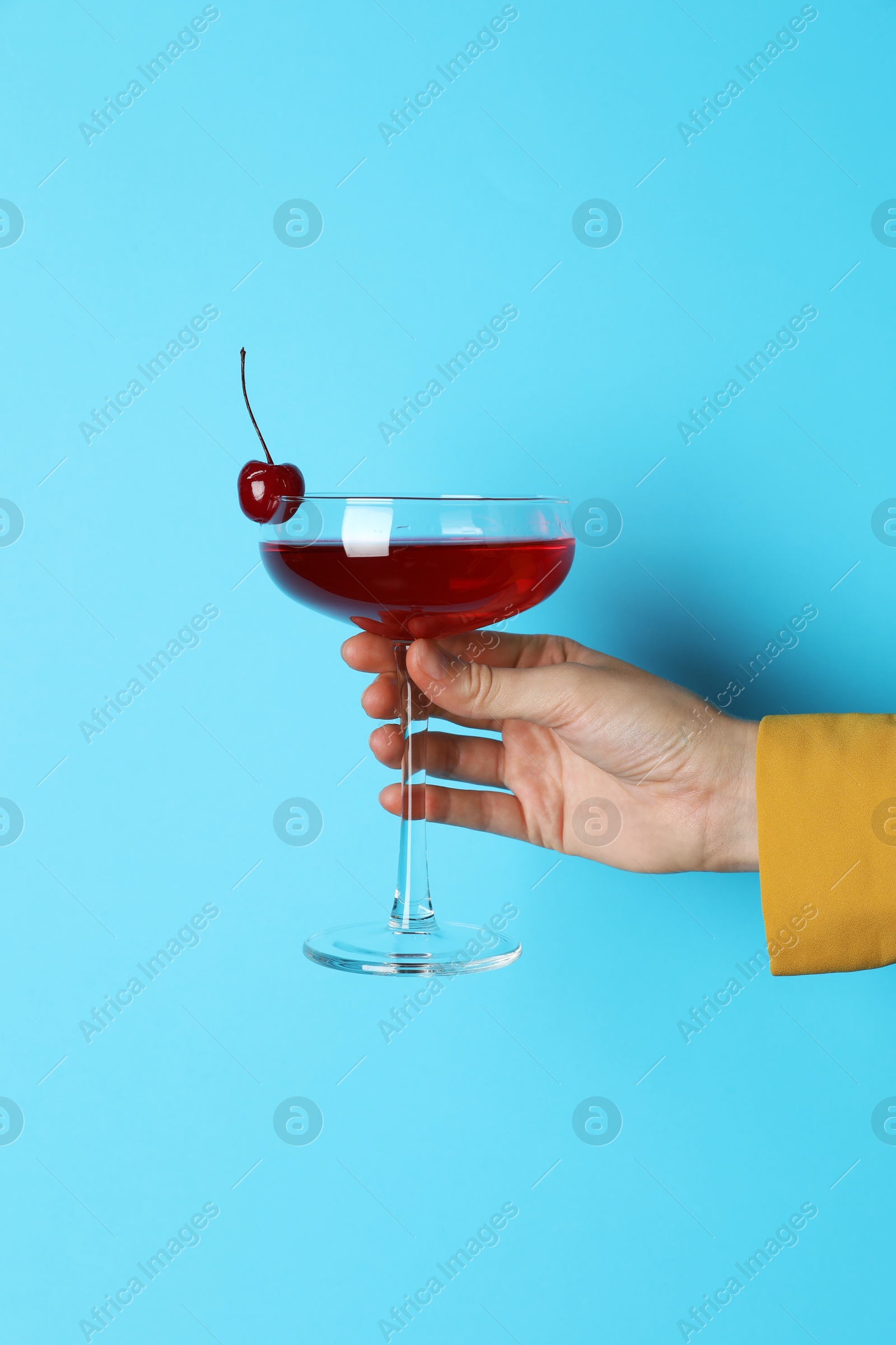 Photo of Woman with glass of refreshing cocktail on light blue background, closeup