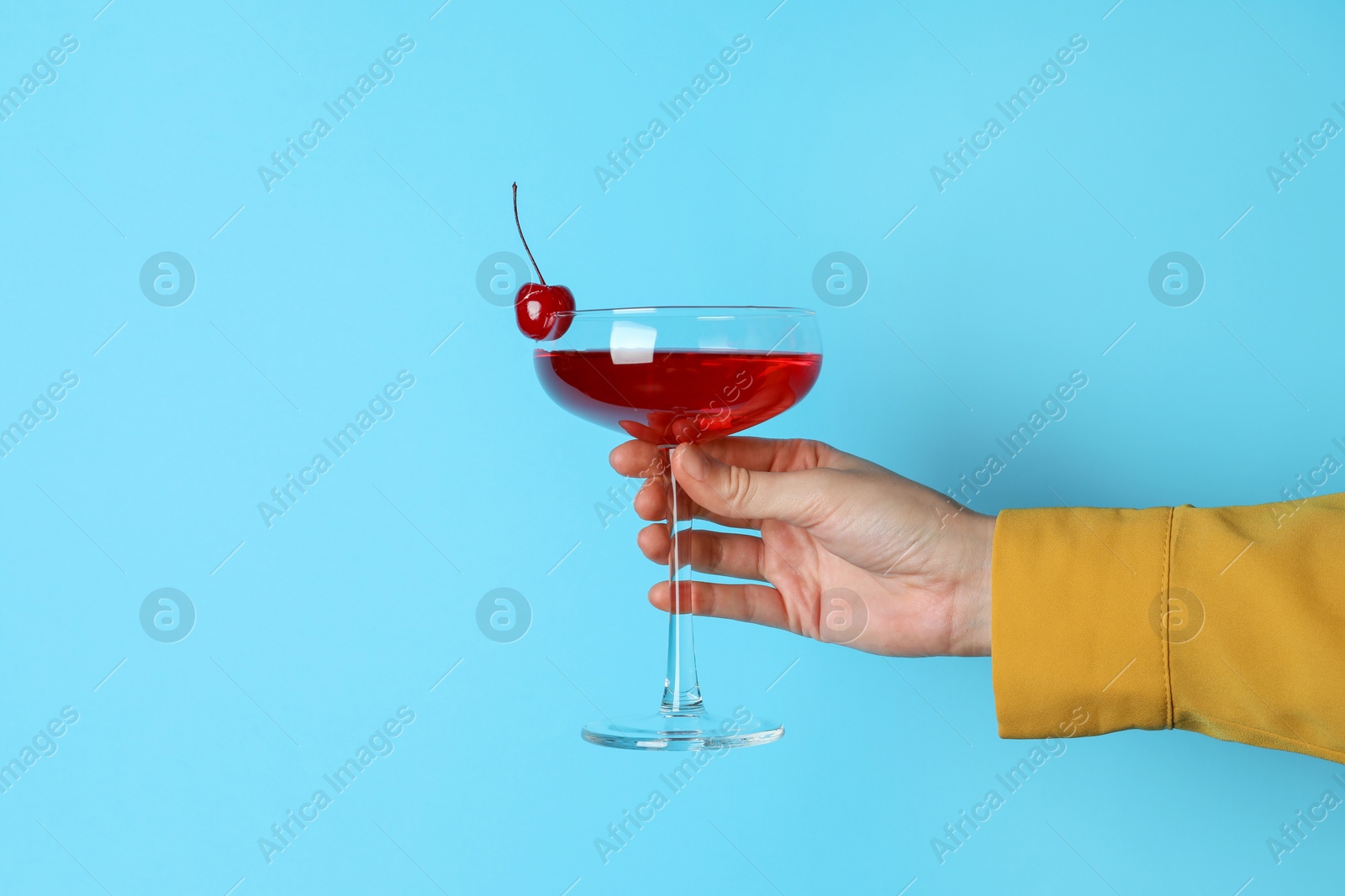 Photo of Woman with glass of refreshing cocktail on light blue background, closeup