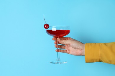 Photo of Woman with glass of refreshing cocktail on light blue background, closeup