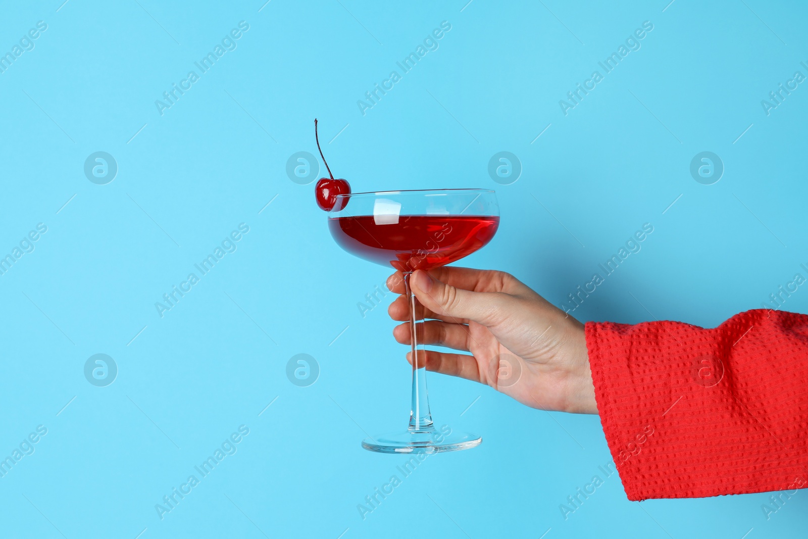 Photo of Woman with glass of refreshing cocktail on light blue background, closeup