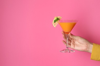 Photo of Woman with glass of refreshing cocktail on pink background, closeup. Space for text