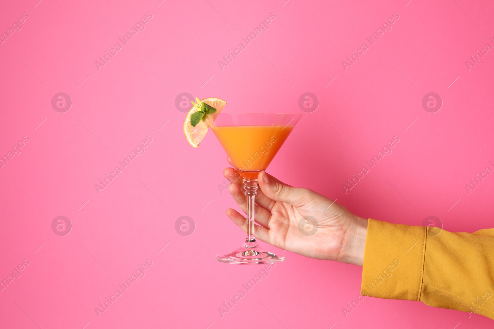 Photo of Woman with glass of refreshing cocktail on pink background, closeup