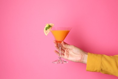 Photo of Woman with glass of refreshing cocktail on pink background, closeup