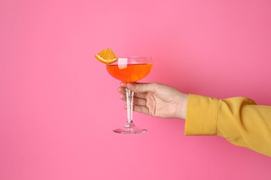 Photo of Woman with glass of refreshing cocktail on pink background, closeup