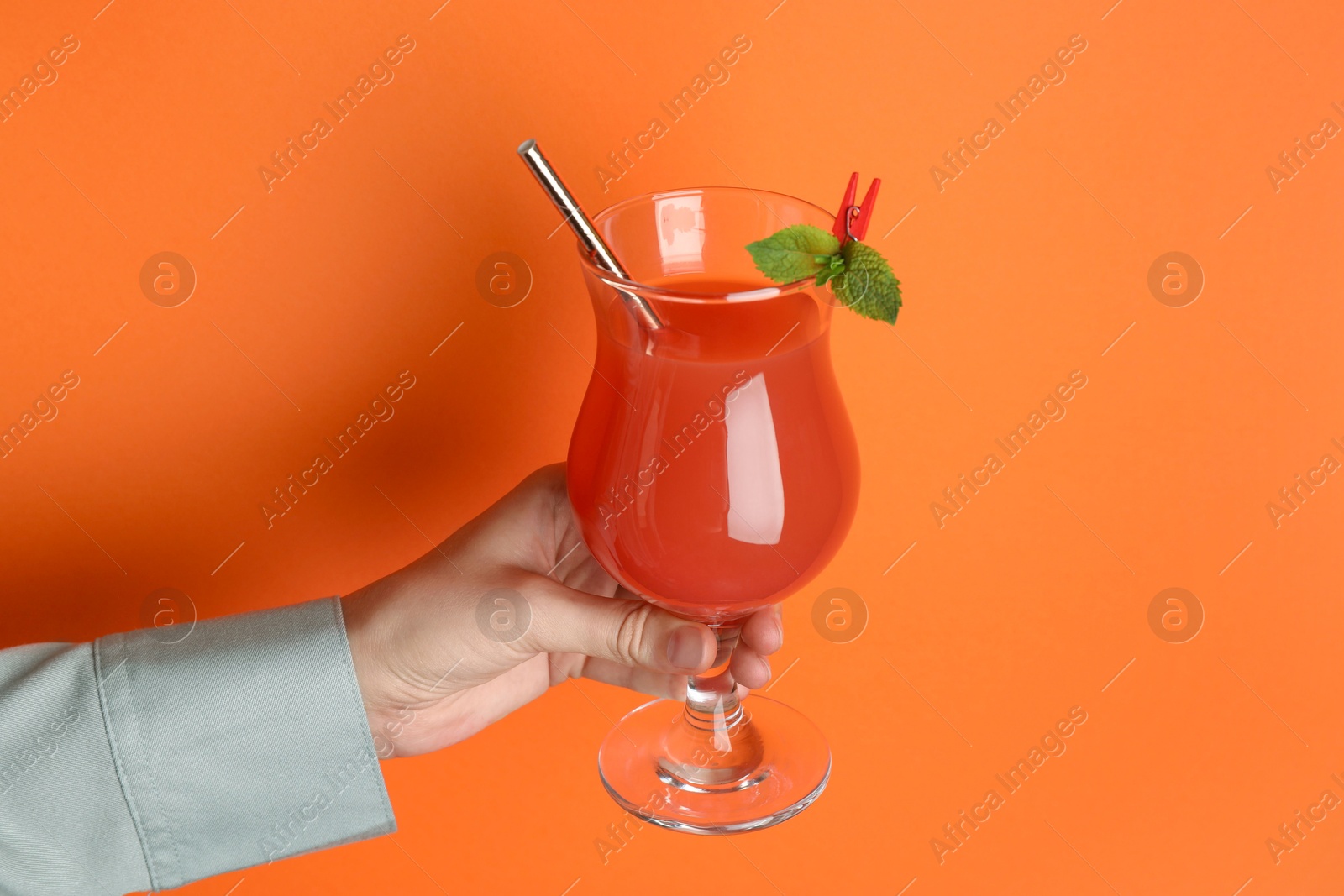 Photo of Woman with glass of refreshing cocktail on orange background, closeup