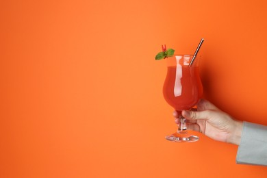 Photo of Woman with glass of refreshing cocktail on orange background, closeup. Space for text