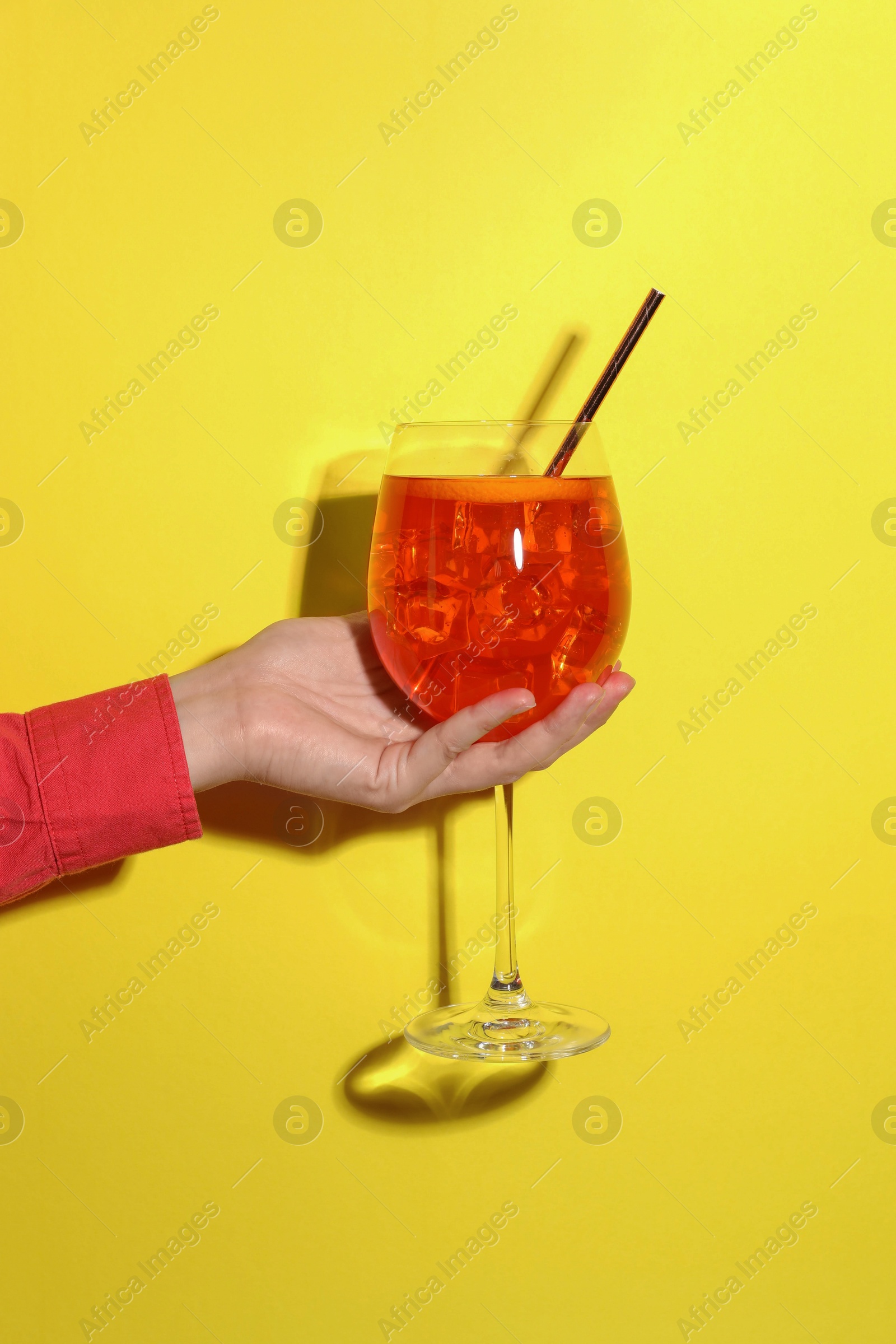 Photo of Woman with glass of refreshing cocktail on yellow background, closeup