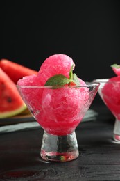 Photo of Tasty watermelon sorbet with mint in glass dessert bowls on black wooden table, closeup