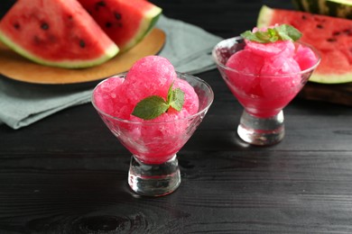 Photo of Tasty watermelon sorbet with mint in glass dessert bowls on black wooden table