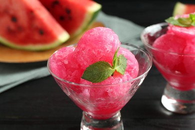 Photo of Tasty watermelon sorbet with mint in glass dessert bowls on black table, closeup