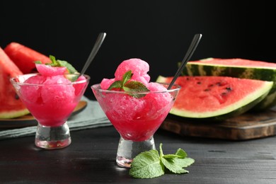 Photo of Tasty watermelon sorbet with mint in glass dessert bowls on black wooden table