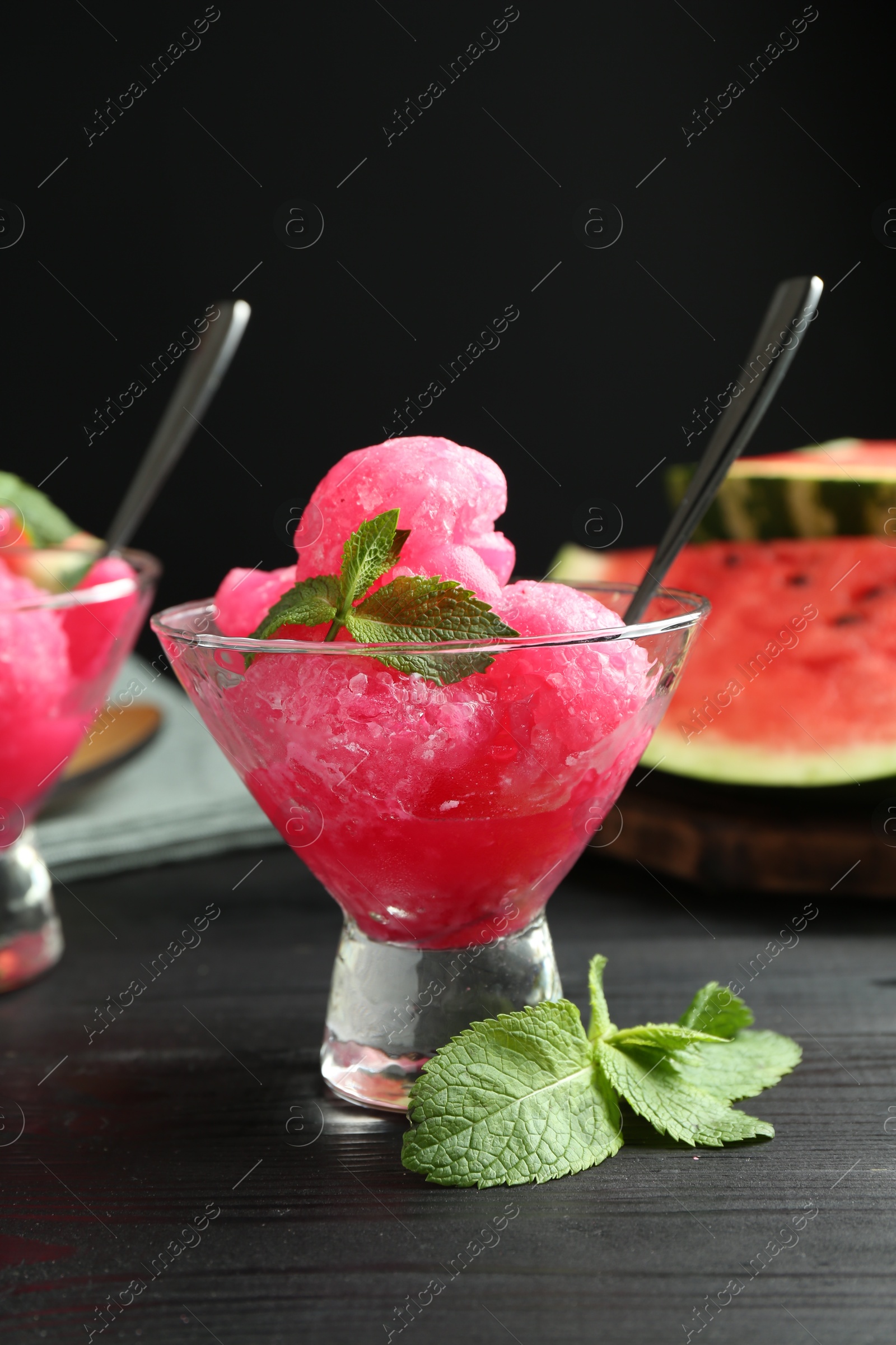 Photo of Tasty watermelon sorbet with mint in glass dessert bowls on black wooden table