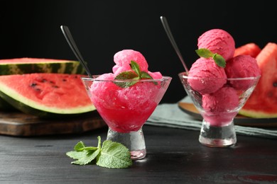 Photo of Tasty watermelon sorbet with mint in glass dessert bowls on black wooden table