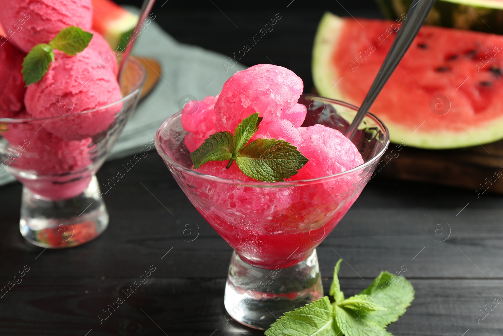 Photo of Tasty watermelon sorbet with mint in glass dessert bowls on black wooden table