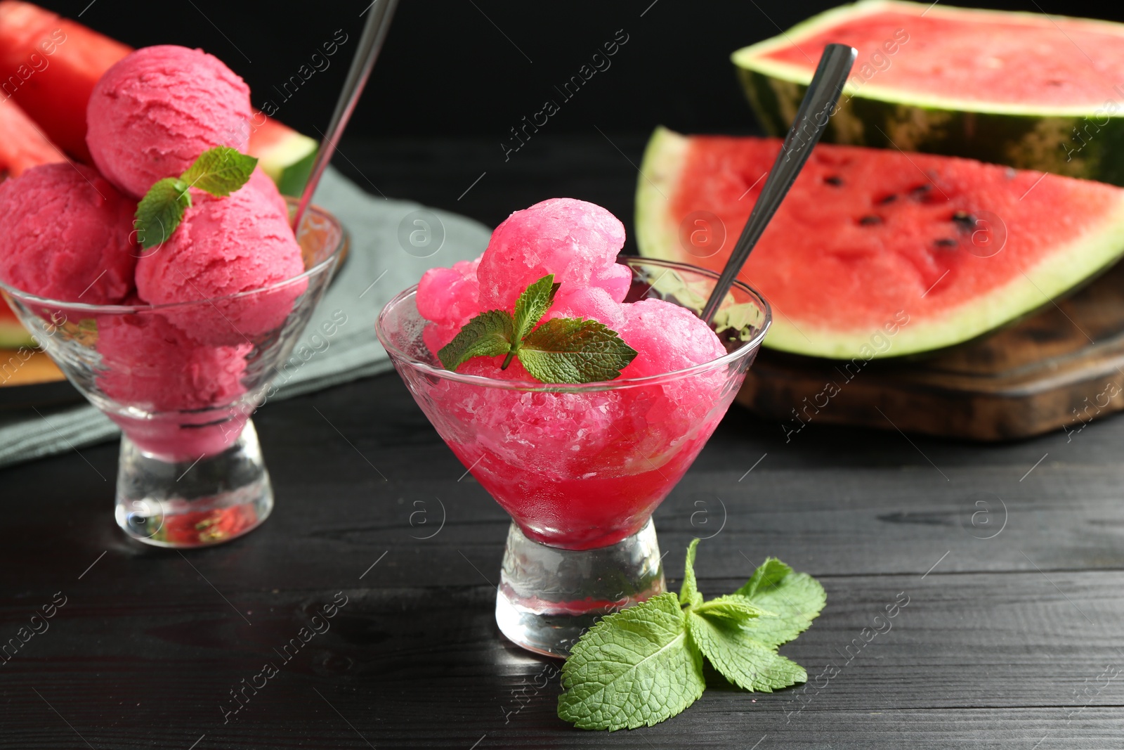 Photo of Tasty watermelon sorbet with mint in glass dessert bowls on black wooden table