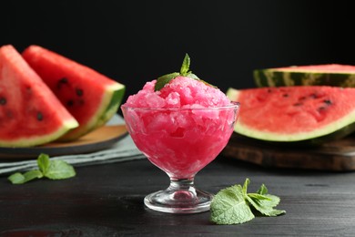 Photo of Tasty watermelon sorbet with mint in glass dessert bowl on black wooden table