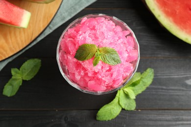 Photo of Tasty watermelon sorbet with mint in glass dessert bowl on black wooden table, flat lay