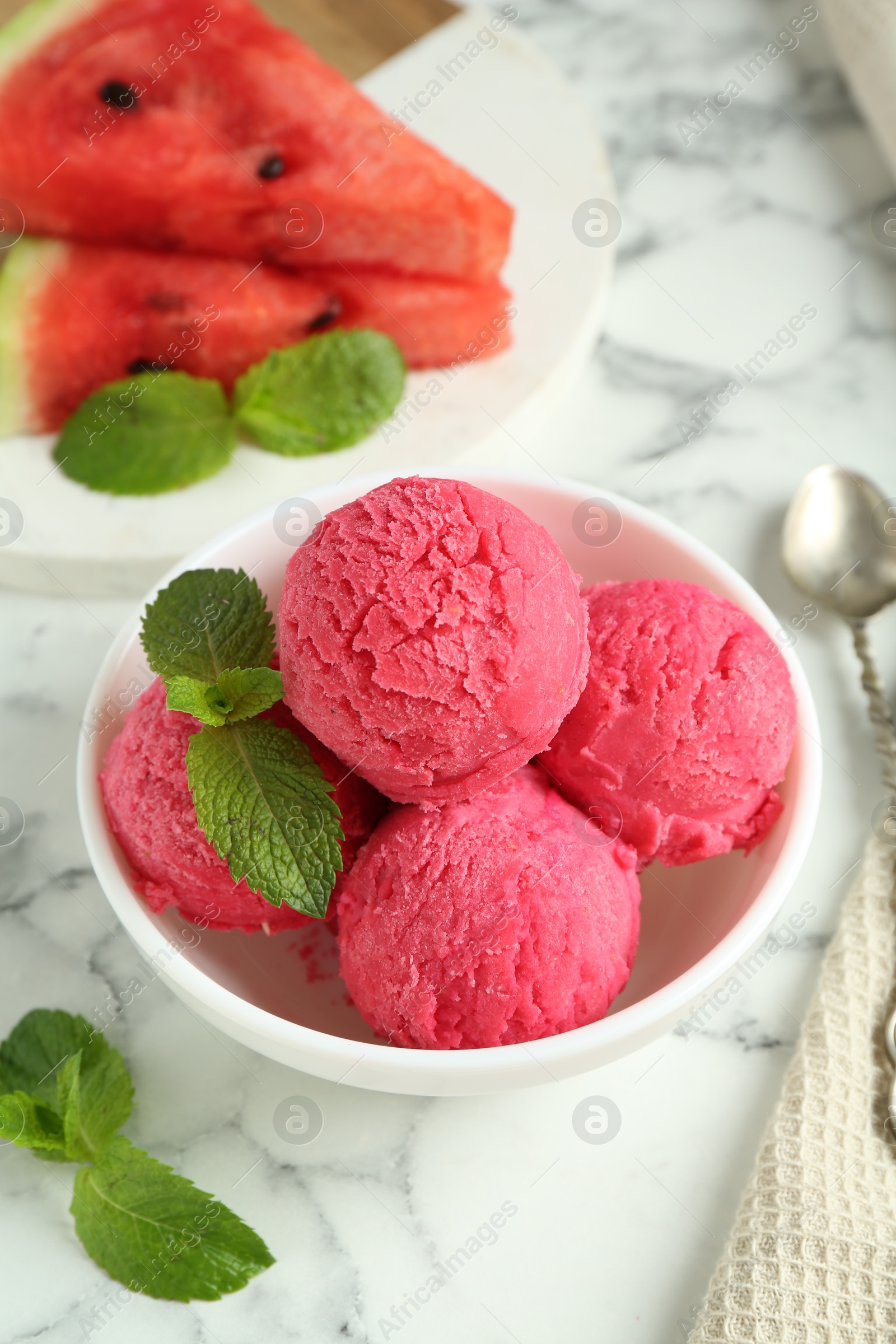 Photo of Scoops of tasty watermelon sorbet with mint in bowl on white marble table