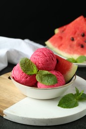 Photo of Scoops of tasty watermelon sorbet with mint and fresh fruit in bowl on grey textured table