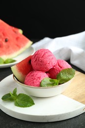 Photo of Scoops of tasty watermelon sorbet with mint and fresh fruit in bowl on grey textured table