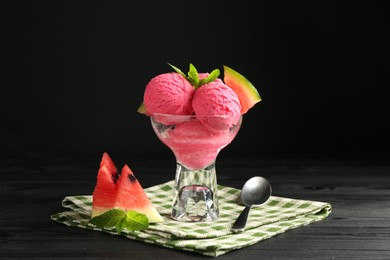 Photo of Scoops of tasty watermelon sorbet in glass dessert bowl with fresh fruit and spoon on black wooden table