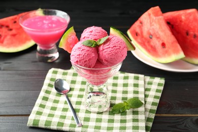 Photo of Scoops of tasty watermelon sorbet with mint, fresh fruit in glass dessert bowl and spoon on wooden table