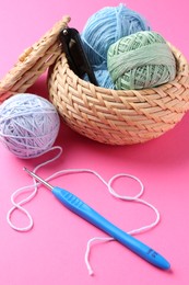 Photo of Different colorful yarns and crochet hook on pink background