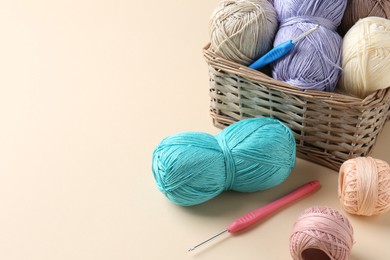 Photo of Different colorful yarns and crochet hooks on beige background. Space for text