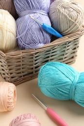 Photo of Different colorful yarns and crochet hooks on beige background, closeup