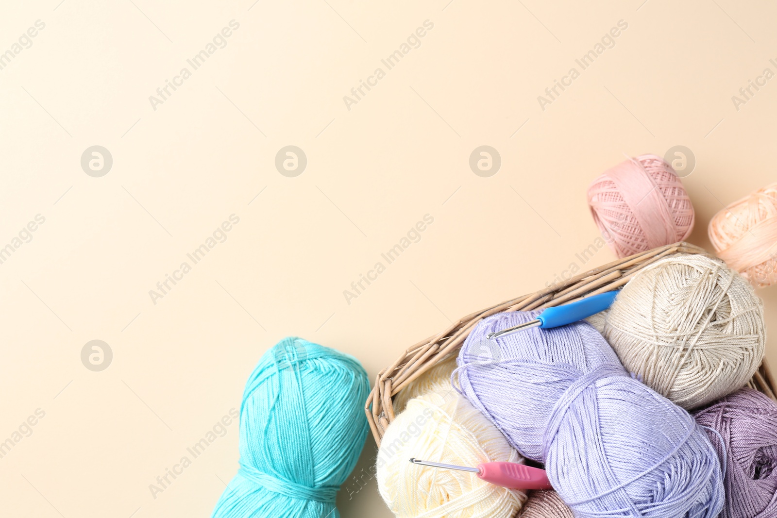 Photo of Different colorful yarns and crochet hooks on beige background, flat lay. Space for text