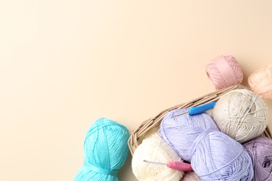 Photo of Different colorful yarns and crochet hooks on beige background, flat lay. Space for text