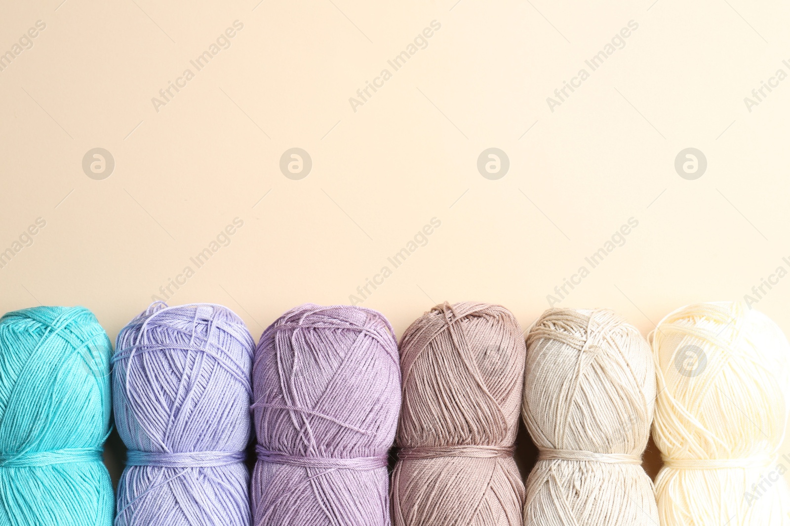 Photo of Different colorful yarns on beige background, flat lay. Space for text