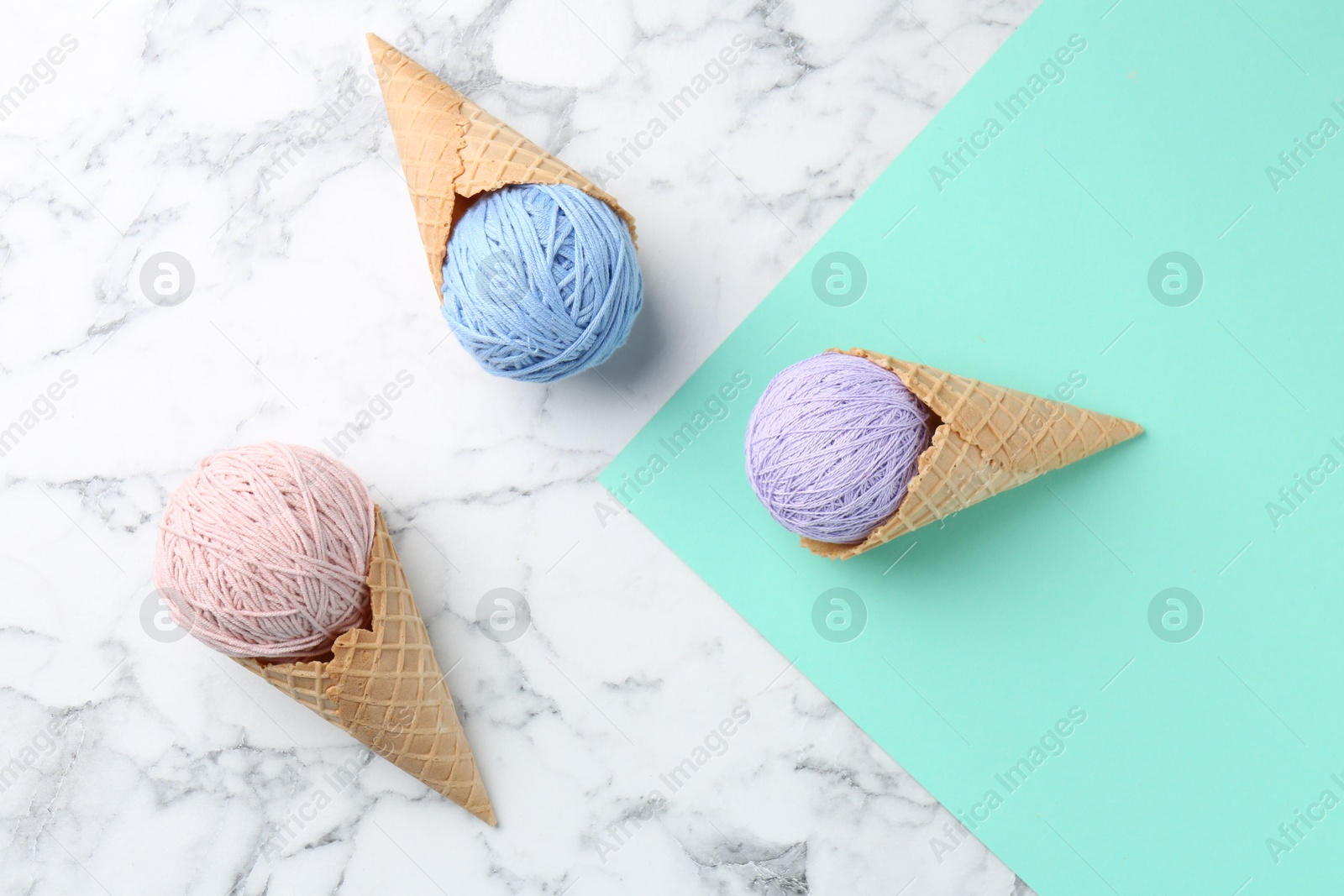 Photo of Ice cream made of colorful yarns and wafer cones on color background, flat lay