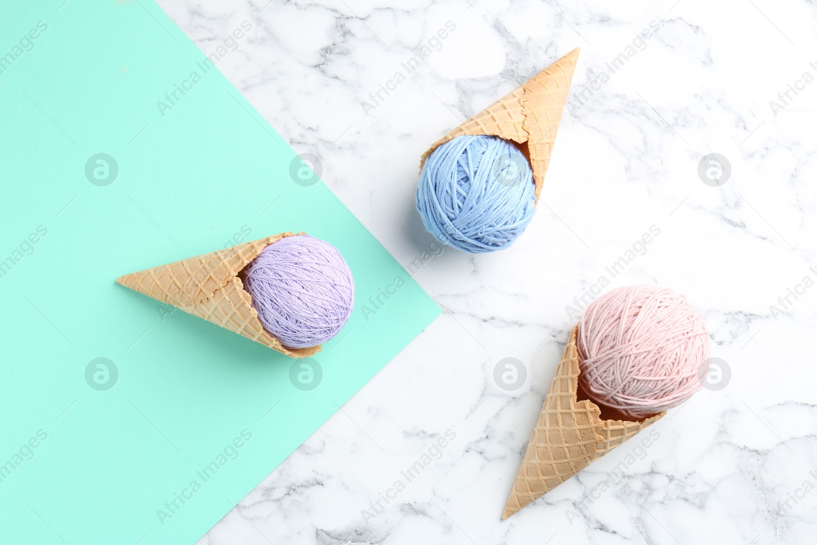 Photo of Ice cream made of colorful yarns and wafer cones on color background, flat lay