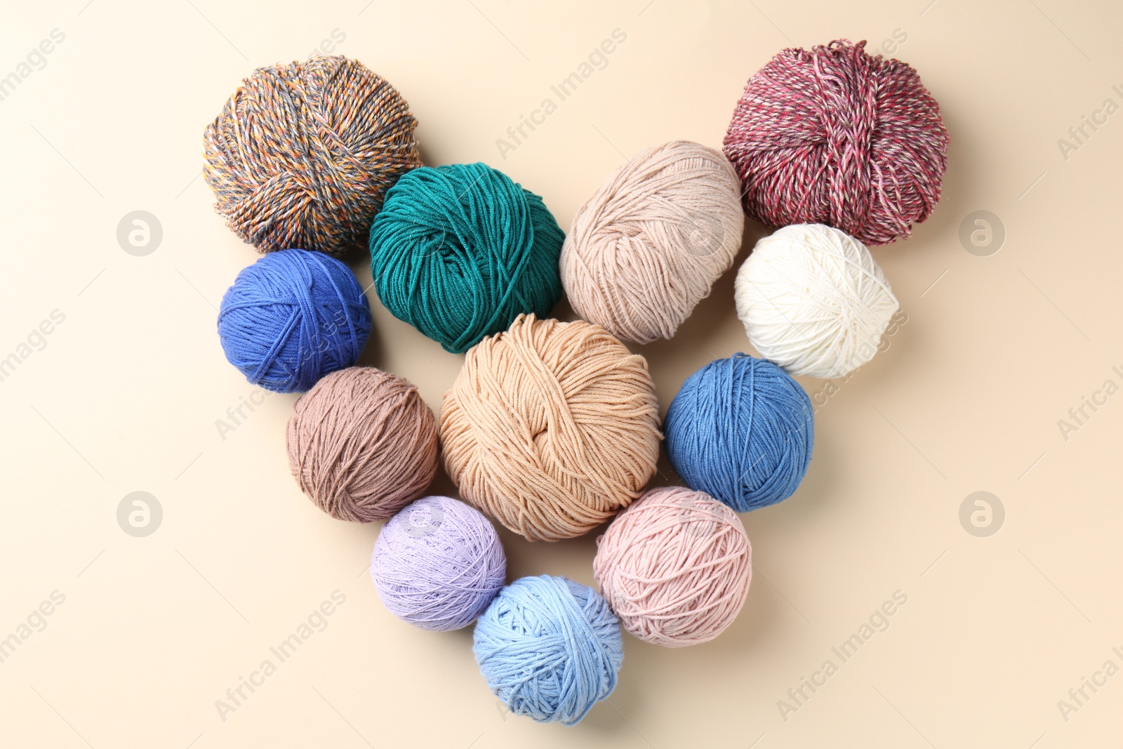 Photo of Heart made of colorful yarns on beige background, flat lay