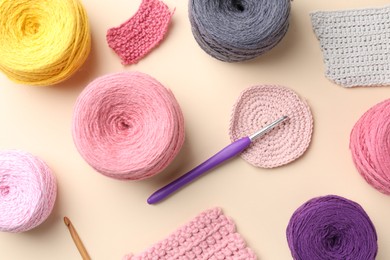 Photo of Different colorful yarns, crochet hook and pattern samples on beige background, flat lay